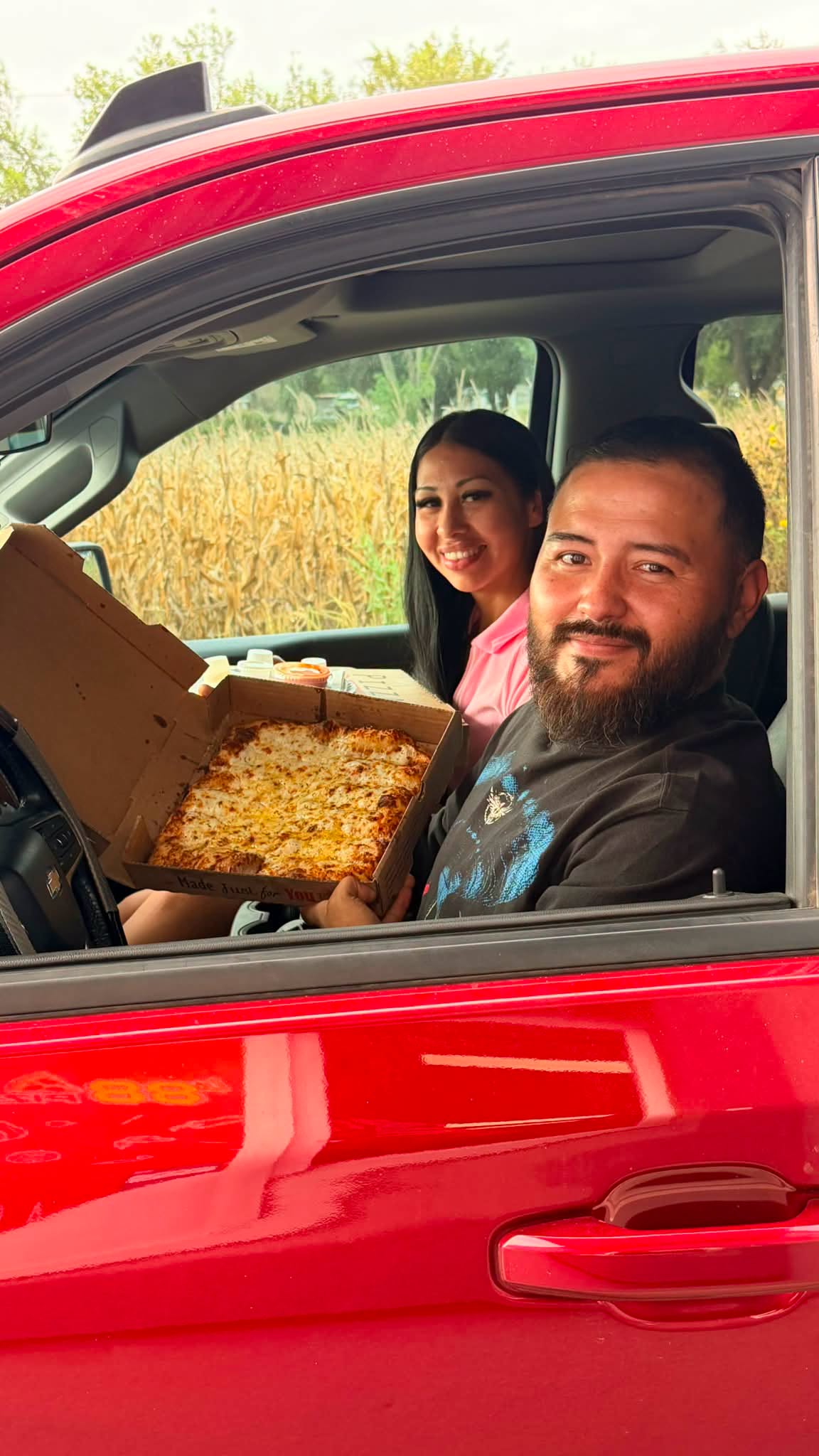 Happy customers with a hot pizza in the car